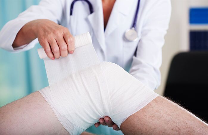 doctor bandaging knee joint with osteoarthritis